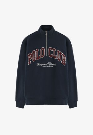 Navy sweatshirt met hoge nek, ritssluiting, voorzijde geborduurde "POLO CLUB" in bordeauxrood en "Beyond Classics" tekst. Zachte stof, ontspannen pasvorm.