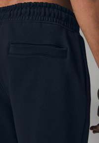 Schwarze Sweatpants aus strukturiertem Stoff mit elastischem Bund und einer Gesäßtasche für die Aufbewahrung. Der Schnitt ist schmal zulaufend für einen figurschmeichelnden Look.