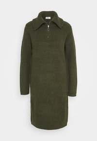 Strikkjole i mørkegrøn med tekstureret ribbing, lange ærmer og en lynlåsekrave med et cirkulært metalaccent. Casual, knælangt design.