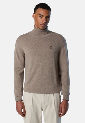 Maglione a collo alto color marrone chiaro realizzato in tessuto morbido. Presenta un design aderente con polsini a coste e un piccolo logo sul petto.