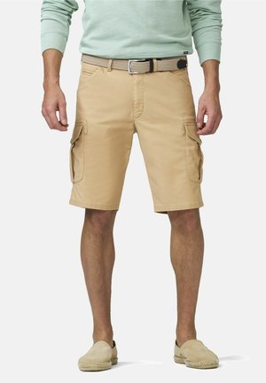 Man draagt beige cargoshorts met zijzakken, een geweven riem, een lichtgroen overhemd met lange mouwen en beige instapschoenen, staand op een witte achtergrond.
