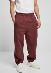 Pantaloni de trening bordo cu un talie elastică, buzunare laterale și manșete elastice, asortați cu adidași albi și un tricou alb simplu.