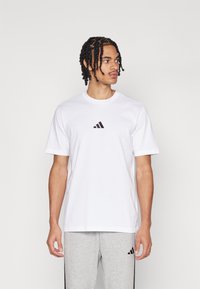 Λευκό βαμβακερό T-shirt με μικρό μαύρο λογότυπο Adidas στο στήθος. Κοντά μανίκια, στρογγυλή λαιμόκοψη, κανονική εφαρμογή, λεία υφή.