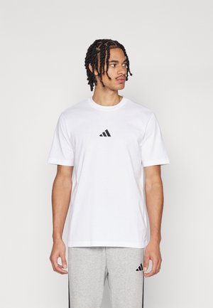 Fehér pamut póló, mellyel egy kicsi fekete Adidas logó van a mellkason. Rövid ujjú, kerek nyakú, normál fazonú, sima textúrájú.