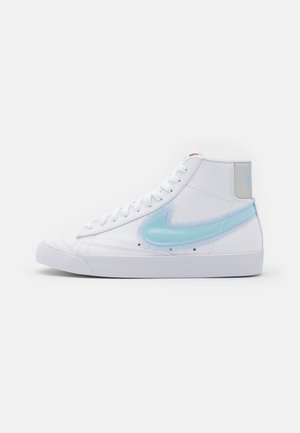 Zapatilla blanca de caña alta con un logo swoosh translúcido de color azul claro y suela de goma blanca, mostrada de lado sobre un fondo liso.