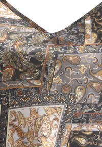 Silk fabric with a paisley pattern in black, gold, and muted tones, featuring intricate detailing and contrasting borders. Satin-like texture.