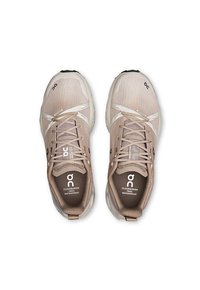 Beige wasserdichte Trailrunning-Schuhe mit textilem Obermaterial, kontrastierenden Schnürsenkeln und prominentem Logo. Verfügt über eine schützende Zehenkappe und eine gepolsterte Sohle.
