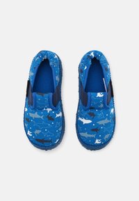 Modré nazouvací boty vyrobené z látky s motivem žraloků v bílé, námořnické a světle modré barvě. Mají elastické boční akcenty a texturované podrážky.