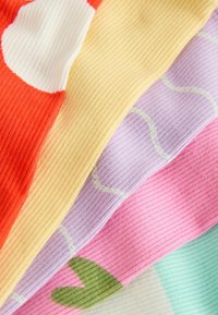 Gros plan de tissus tricotés côtelés colorés avec des motifs abstraits en orange, jaune, violet, rose et vert menthe.