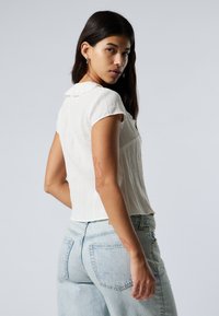 Valge linane lühikeste varrukatega pluus koos kraega, tekstureeritud pind ja slim-fit disain. Ühendatud heledate siniste kõrge vöökohaga teksadega.