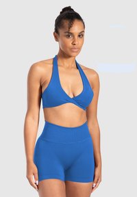 Blauwe halter crop top met een gedraaide frontontwerp en bijpassende hooggeprijsde shorts. Gladde textuur, rekbare stof en getailleerde pasvorm.