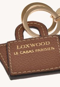 Porte-clés en cuir marron avec le texte doré en relief "LOXWOOD LE CABAS PARISIEN", doté d'un anneau en métal doré et de détails de surpiqûre contrastés.