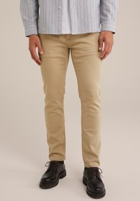 Beige slim-fit chinos i en bomullsblandning, med en slät yta och rena linjer, matchade med svarta snörskor.