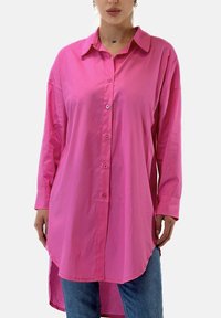Långärmad skjorta med knappar i ljusrosa, med krage, slät tygstruktur och rundad fåll för en avslappnad passform.
