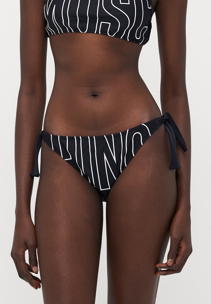 Black bikini bottom with tie side detailing, featuring white vertical stripes and text pattern. Made from smooth swimwear fabric.