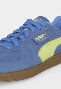 Μπλε σουέντ αθλητικό παπούτσι Puma Palermo με ανοιχτοπράσινη ρίγα και λογότυπο, μπλε κορδόνια και καφέ υφασμένη σόλα.