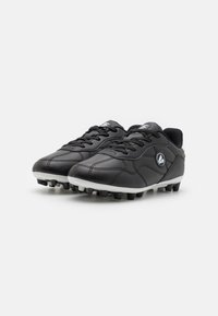 Botas de fútbol negras con parte superior de cuero sintético, superficie texturizada, suela blanca y tacos negros. Presenta un diseño con cordones y un detalle del logo.