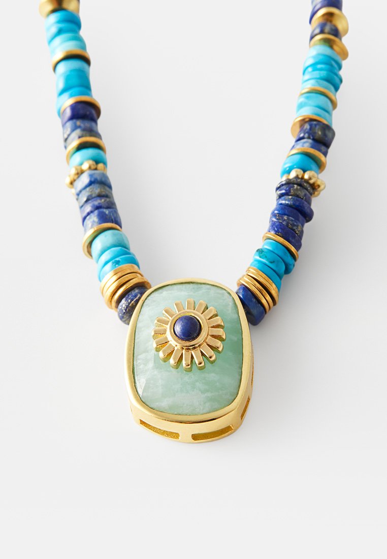Perlenkette mit Türkis, Lapislazuli und goldenen Akzenten. Enthält einen großen grünen Steinanhänger mit einem Sonnenstrahlen-Design und einem blauen Edelstein in der Mitte.