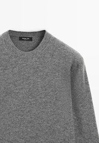 Pull en maille grise à col rond, avec des poignets et un ourlet côtelés. Fabriqué dans un matériau doux, présentant une texture subtile et sans motifs visibles.