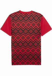 Rdeča majica s kratkimi rokavi, ki ima na hrbtni strani črn geometrijski spiralen vzorec, z gladko teksturo in zasnovo kroga.