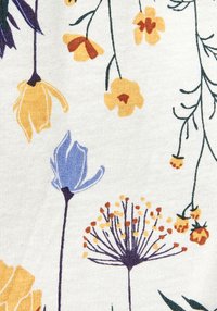 Vit tyg med ett blommönster med gula och blå blommor, gröna stjälkar och orange detaljer, allt på en strukturerad yta.