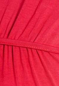 Tecidos elásticos vermelhos com uma textura subtil, apresentando detalhes franzidos e uma cintura suave para um ajuste estruturado e conforto.