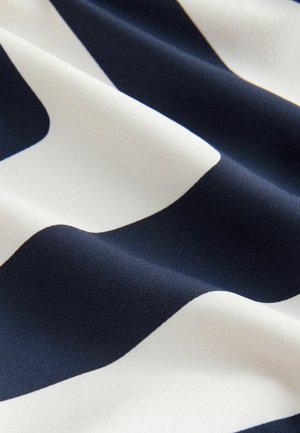 Marineblauwe en witte stof met een gladde textuur, voorzien van golvende patronen. Het kleurcontrast versterkt de visuele aantrekkingskracht van het ontwerp.