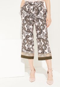 Culottes blancs à motifs en rose, noir et marron, ornés de dessins paisley et floraux, avec un ourlet vert et une taille nouée.