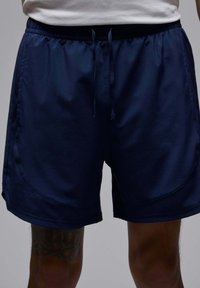 Mørkeblå atletiske shorts lavet af glat stof, med en elastisk talje og en snor, samt side søm detaljer.