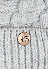 Hall kokku kootud hall beanie, millel on soonikkoes tekstuur, paks punutud muster ja ümmargune metallist logotagi musta kirjaga.