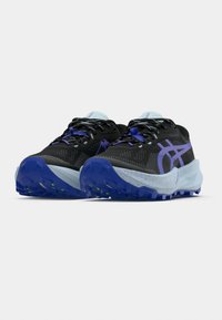 Μαύρα αθλητικά παπούτσια με μωβ λεπτομέρειες και δίχτυ στην πά νω επιφάνεια. Διαθέτουν ανάγλυφη μπλε σόλα με σχεδιασμό με κηλίδες και ανακλαστικές λεπτομέρειες.