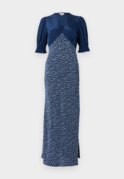 Marineblauwe jurk met een V-hals, pofmouwen en een witte stippenpatroon. Heeft een aansluitende lijfje en een lange rok met een split aan de zijkant.