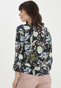Bluse mit floralem Muster auf navyfarbenem Hintergrund, mit blauen, grünen und pinken Blumen. Dreiviertelärmel mit umgeschlagenen Bündchen. Weicher Stoff.