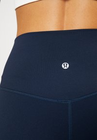 Leggings a vita alta di colore blu navy realizzati in tessuto elastico, dotati di un piccolo logo in vita e cuciture piatte per un comfort ottimale.