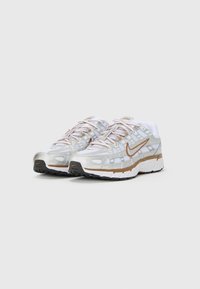 Nike trkačke cipele s gornjim dijelom od srebrne mrežice s bijelim detaljima, narančastim swooshom i teksturiranim crno-bijelim potplatom.