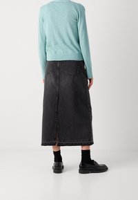 Light blue long-sleeve top paired with a black denim midi skirt featuring a back slit, two rear pockets, and frayed hem details.
