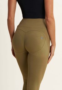 Leggings verde oliva con un alto giro vita, tessuto elastico e dettagli di cucitura sul retro. Presenta un piccolo logo ricamato.