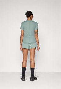 Mint green athletic outfit consisting of a fitted t-shirt and shorts. The fabric is smooth, with a seam running down the back. Black socks and shoes.