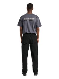 Bărbat văzut din spate, purtând un tricou gri cu textul „High Altitude Low Opening” și pantaloni cargo negri, stând în fața unui fundal alb.