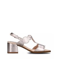 Sandalia de tacón metálica plateada con diseño de ondas, punta abierta, correa al tobillo y tacón cuadrado para estabilidad y comodidad.