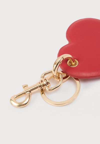 Κόκκινο δερμάτινο μπρελόκ σε σχήμα καρδιάς με χρυσό μεταλλικό κλιπ και κρίκο, με λεία υφή και στρογγυλεμένες άκρες.