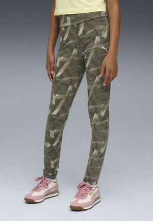 Zöld mintázatú leggings absztrakt világosszürke dizájnnal, magas derékkal és Puma logóval. Rózsaszín sportcipővel, fehér díszítésekkel párosítva.