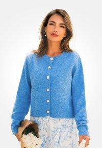  Lichtblauwe, knoopsluitende cardigan van zachte, gestructureerde brei met een ronde hals en lange mouwen. Voorzien van ronde knopen en geribbelde mouwuiteinden.