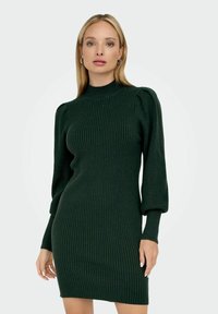 Robe en maille côtelée verte avec un col montant, des manches longues bouffantes et une silhouette ajustée.