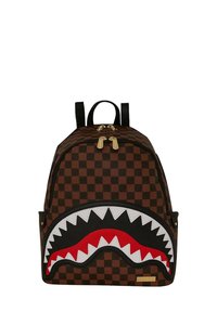 Zaino a scacchi marrone con un design a bocca di squalo in bianco e nero con dettagli rossi, cerniere dorate e doppie tracolle nere.