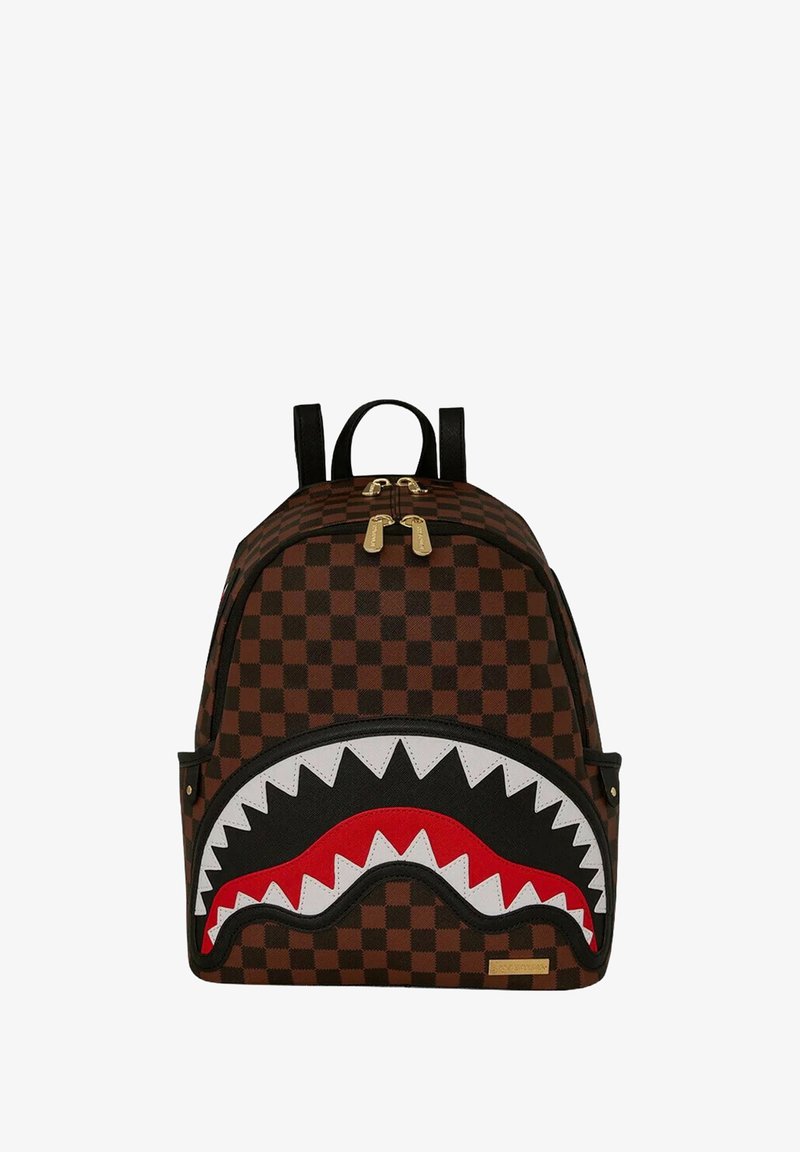 Zaino a scacchi marrone con un design a bocca di squalo in bianco e nero con dettagli rossi, cerniere dorate e doppie tracolle nere.