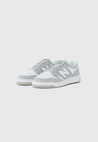 Sneaker bianche e grigie chiare con punta perforata, colletto imbottito e logo "N" in contrasto sui lati; suola in gomma con battistrada testurizzato.