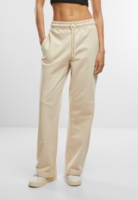 Beige Jogginghosen mit elastischem Bund, Kordelzug, Seitentaschen und lässiger Passform, aus weichem Baumwollmischgewebe gefertigt.