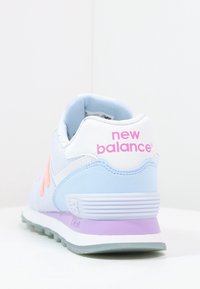 Baskets bleu clair avec accents blancs, logo rose et surface texturée. Elles présentent une semelle intermédiaire violette et un design arrondi et rembourré.