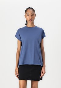 Blaues Baumwoll-T-Shirt mit kurzen Ärmeln und rundem Ausschnitt, kombiniert mit einem schwarzen Jeansrock. Schlichtes, lockeres Design.